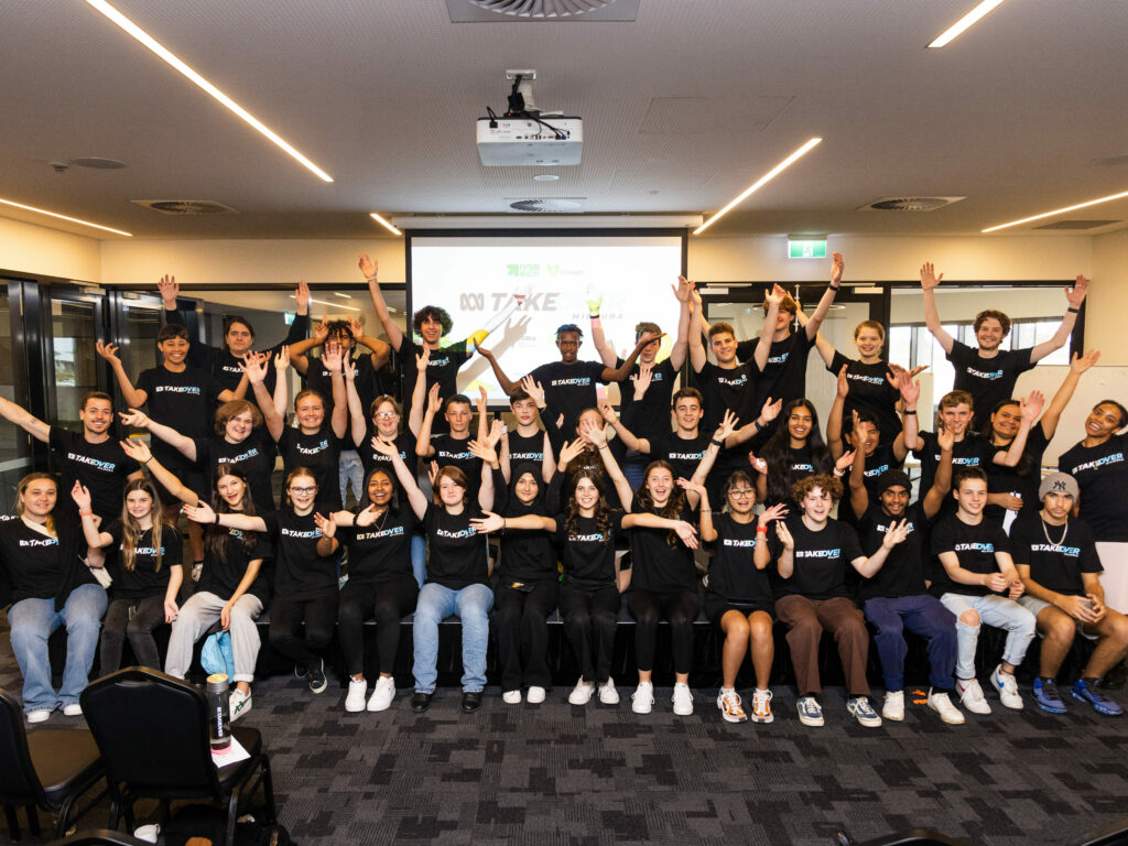 Group of young people sitting and stand with their arms outstretched.