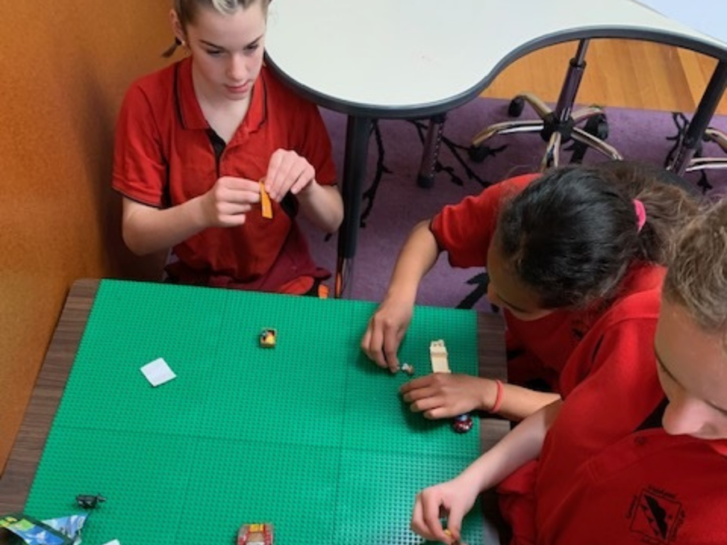 Three girls sitting around a table building Lego to develop STEM skills.