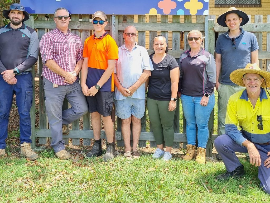 IMAGE: Group of people standing in front of fence. PROGRAM: Telstra’s Connected Communities Grant Program.