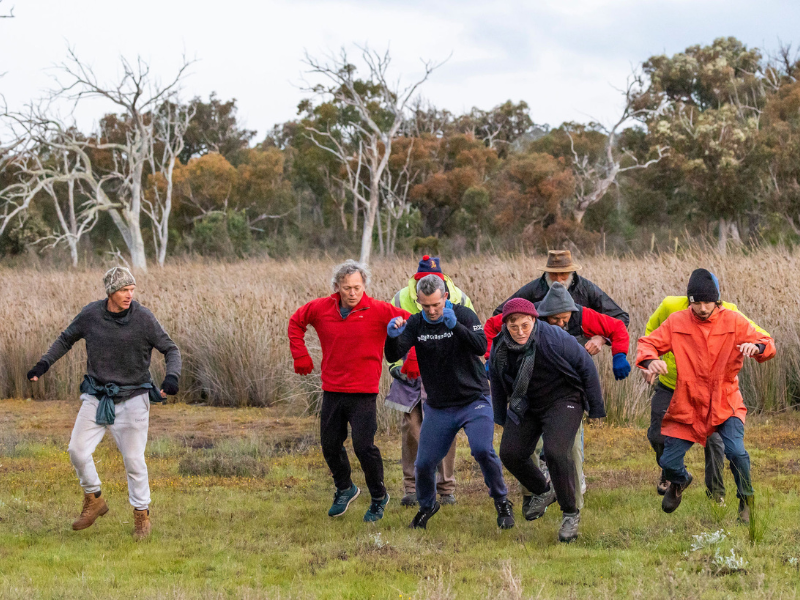 A group of men are captured jumping as they dance in a field. 