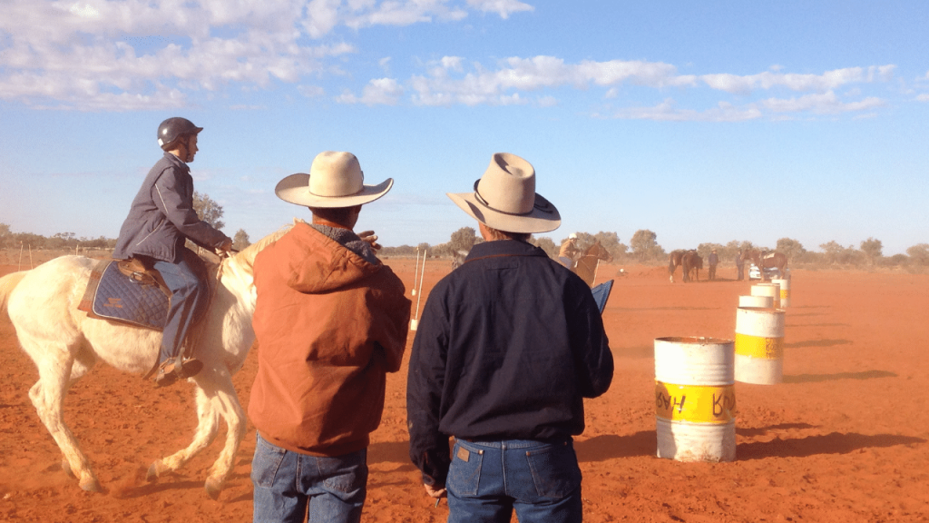Two men watching a boy riding a horse, drought grants