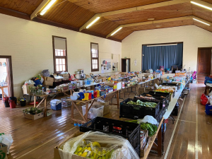 IMAGE: Community Hall with boxes of food lining the space. HEADING: Vital funding already supporting flood-affected Victorian communities