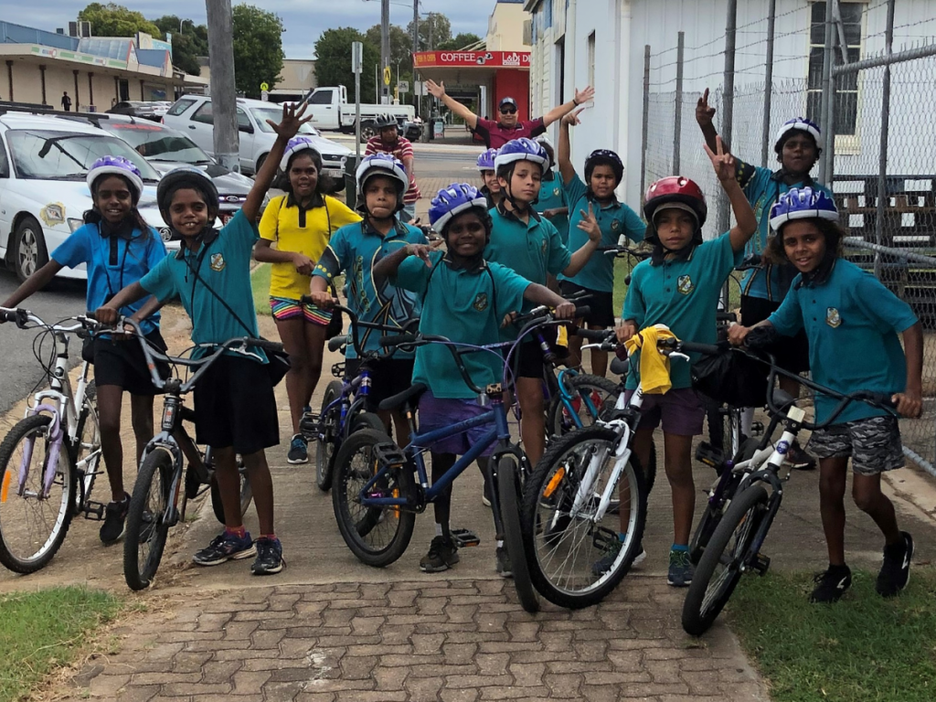 HEADING: Expanding chaplaincy services for rural Queensland schools. IMAGE: Groups shot of children with their bikes.
