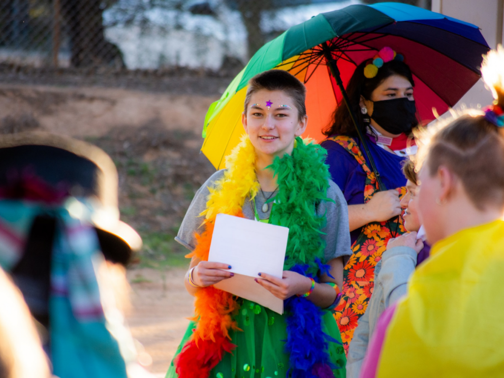 HEADING: Funding available to bring youth-led initiatives to life. IMAGE: Riverland Youth Theatre member in rainbow feather boa.