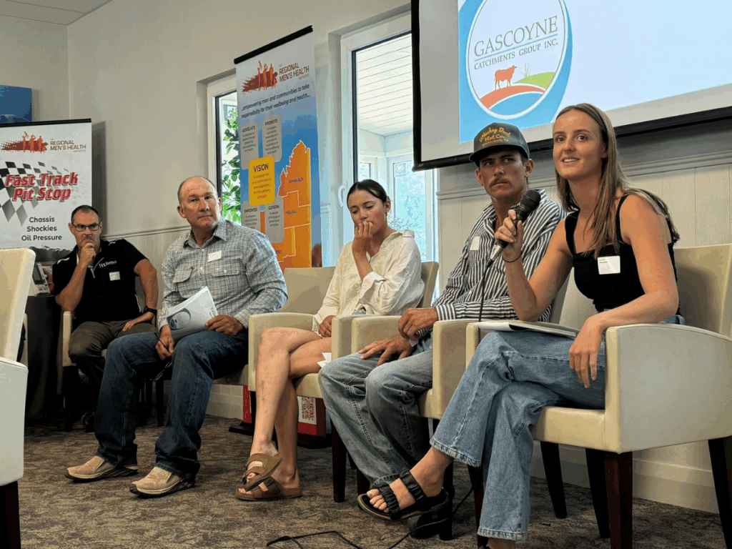 Five people are seated in front of an interactive whiteboard, one woman holds a microphone. 