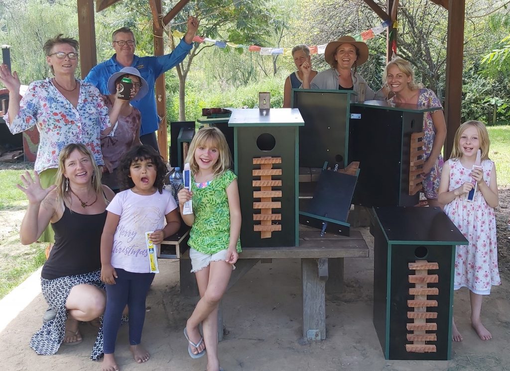 HEADING: Rural communities given a $1.7 million boost. IMAGE: Group of people smile and wave at camera with birdfeeders.