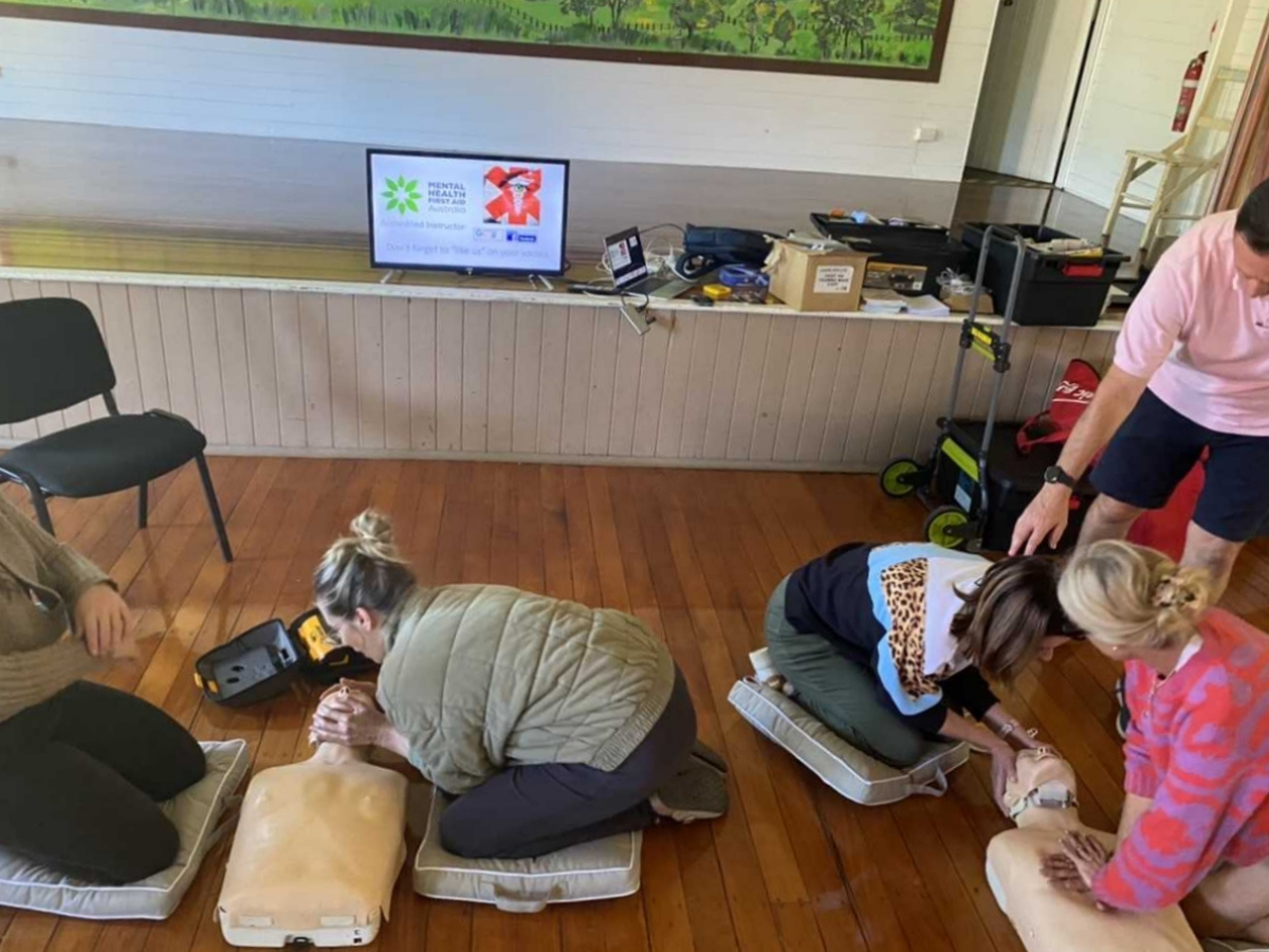 People kneeling down learning first aid on dummies, with computer in the background.