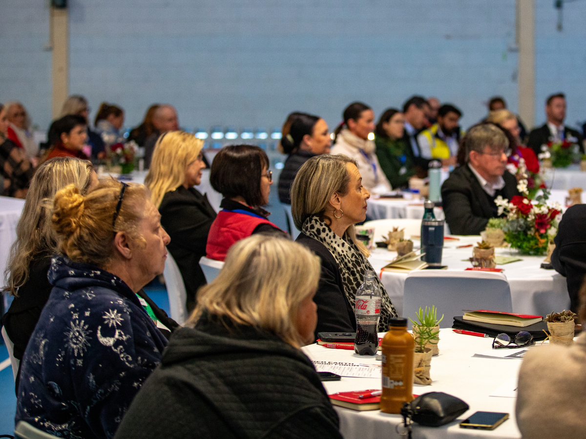 Side-on view of people sitting around tables at a conference