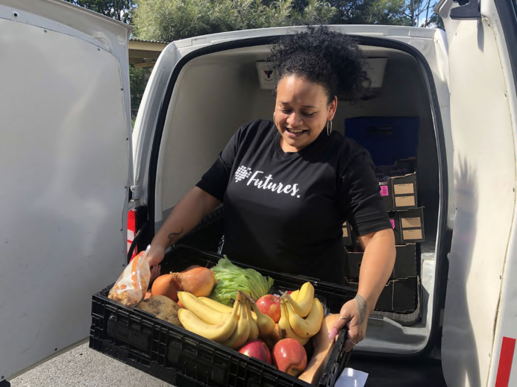 Woman unloading fruit box out of the back of a van