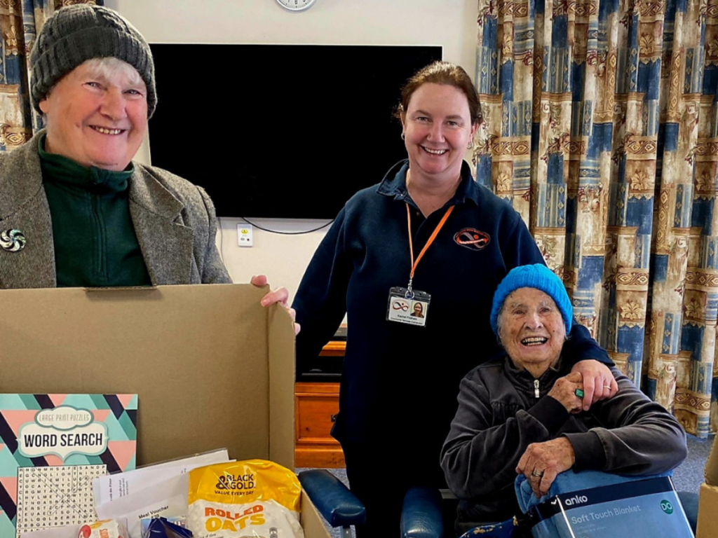 Volunteers with an older person, packing a food hamper.
