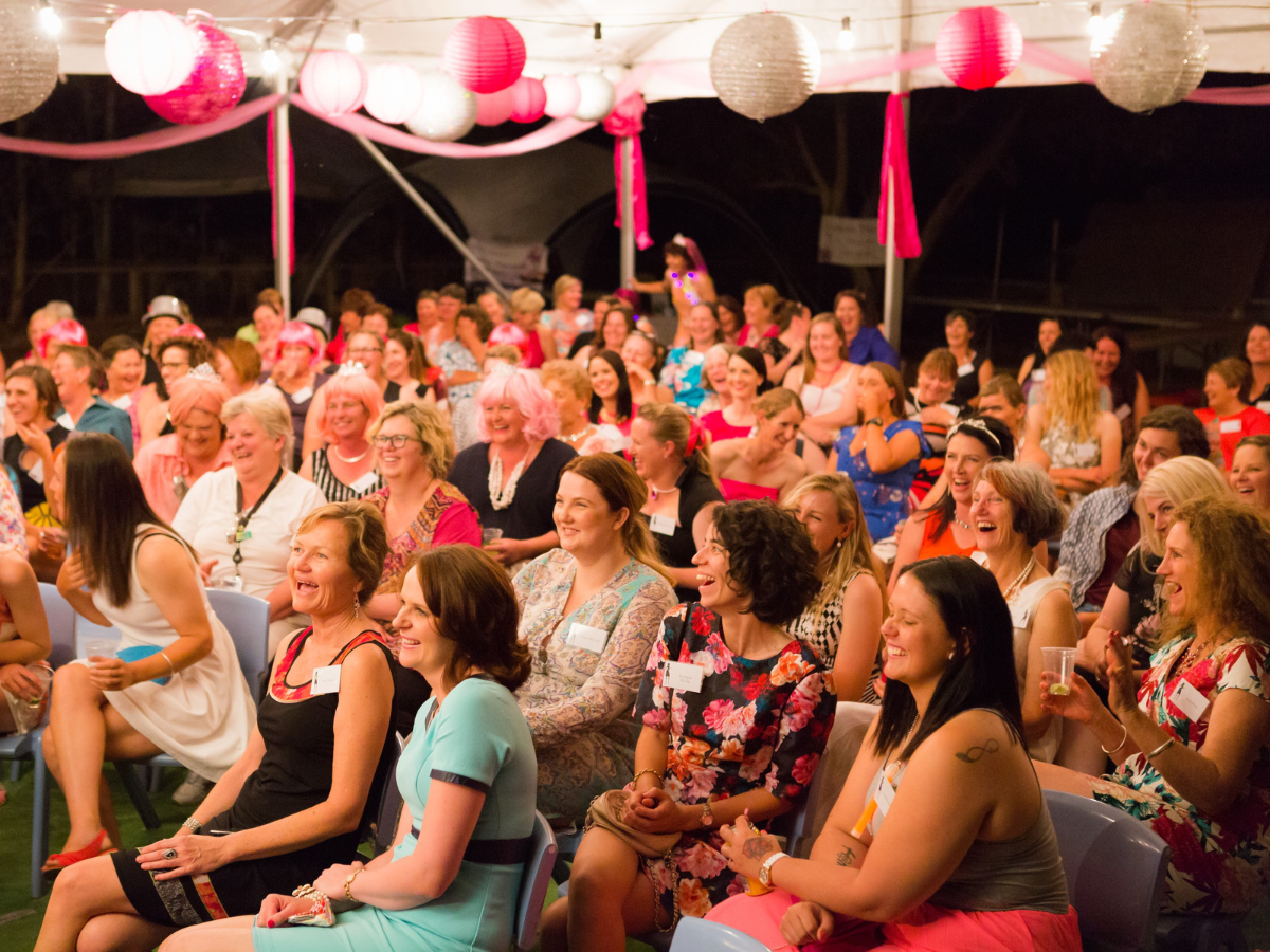 Laughing and smiling women sitting under a marquee.