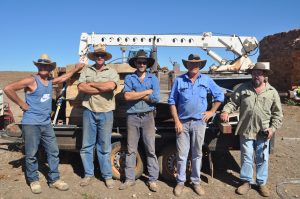 Five men in work gear stand in front of machinery