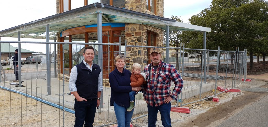Two men, a woman and a toddler stand in from of the Orroroo rotunda rebuild in progress