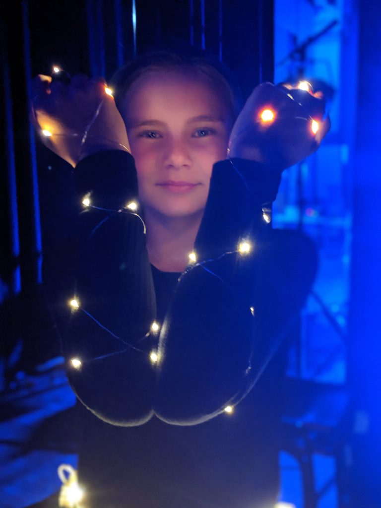 A girl is wrapped in fairy lights for a performance