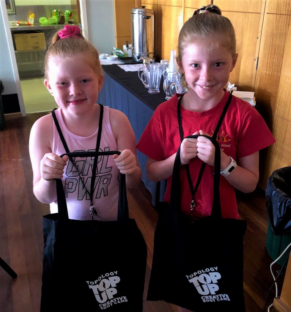 Two young girls show off their Topology bags