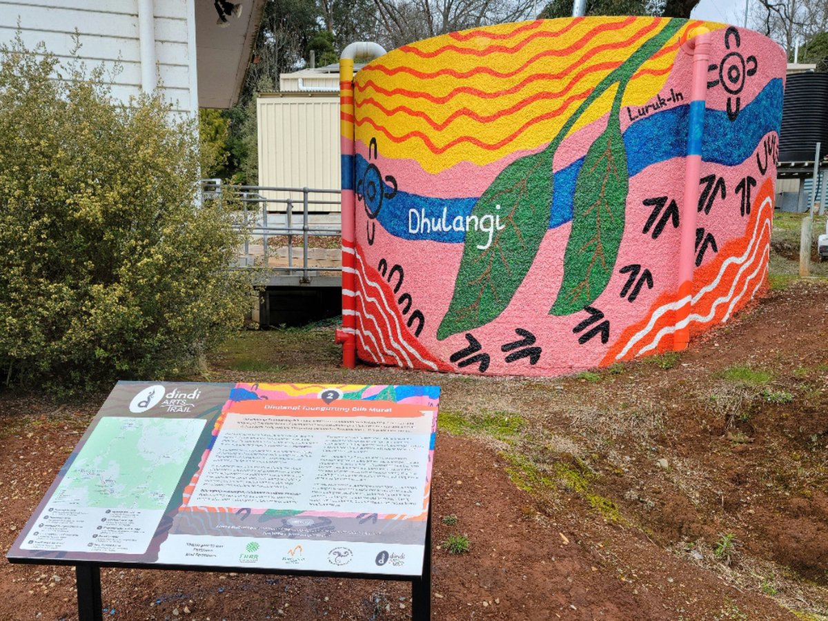 Mural painted on a water tank with interpretive signage in the foreground.