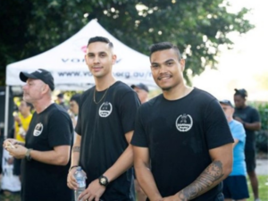 Two young adults facing the camera and a man standing sideways with a marquee in the background.